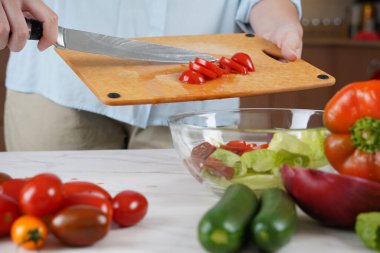 Sebze salatası yapan kadın. Domatesleri ahşap masada kesen ellere yakın çekim