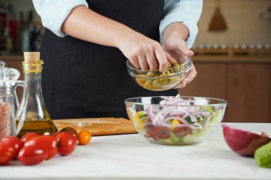 Kız taze sebze salatasına zeytin ekliyor. Sebze salatası hazırlayan kız..