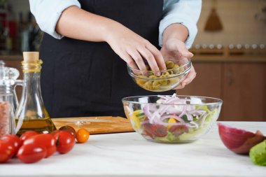 Kız taze sebze salatasına zeytin ekliyor. Sebze salatası hazırlayan kız..
