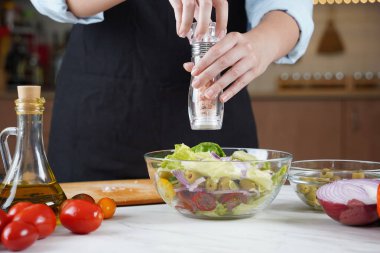 Kız taze sebze salatasına tuz serpiyor. Sebze salatası hazırlayan kız..