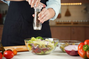 Kız taze sebze salatasına karabiber serper. Sebze salatası hazırlayan kız..