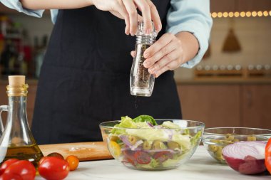Kız taze sebze salatasına karabiber serper. Sebze salatası hazırlayan kız..