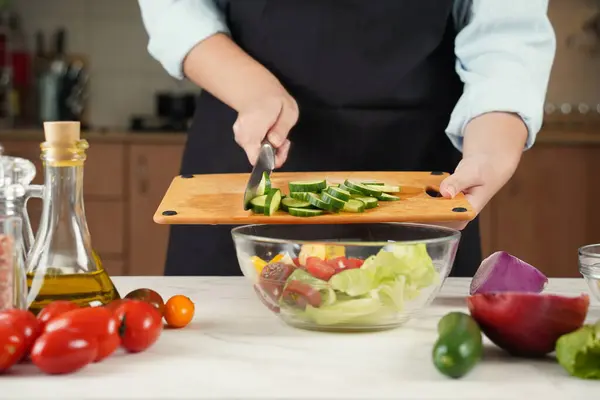 野菜サラダを作る過程にある女性 木製カッティングボードの手切断キュウリのクローズアップ — ストック写真
