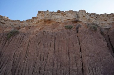 Güneşli bir günde dalgalı deniz kıyısı ve mavi gökyüzü. Deniz Burnu, Akdeniz kıyıları, kaya ve taş katmanları.