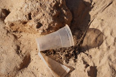 Plastik kirliliği. Plajda boş plastik bardak. Kirlilik konsepti. Boş içecek paketlerini çöpe at