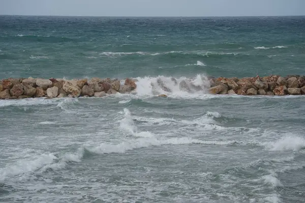 Strong currents and waves in the sea. Waves successfully crash into the stone breakwater.