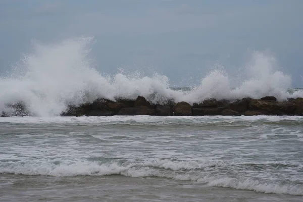 Strong currents and waves in the sea. Waves successfully crash into the stone breakwater.