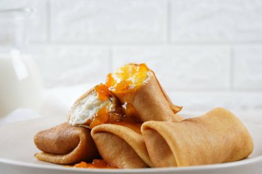 Kahvaltı için tatlı süzme peynirli krep ve şeftali reçeli.