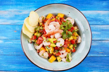 Mavi arka planda karides, mango ve avokadoyla Ceviche salatası. Latin Amerika yemekleri. Lezzetli, taze yapılmış karides ceviche. Limon ve portakalla marine edilmiş karides. .