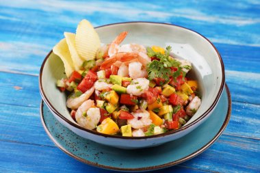Mavi arka planda karides, mango ve avokadoyla Ceviche salatası. Latin Amerika yemekleri. Lezzetli, taze yapılmış karides ceviche. Limon ve portakalla marine edilmiş karides. .
