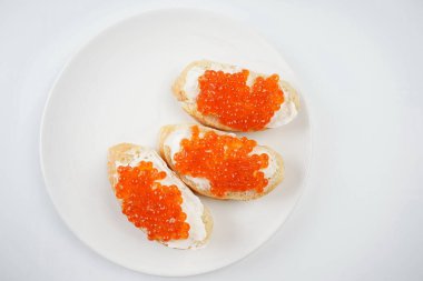 Beyaz tabakta kırmızı havyarlı ekmek dilimleri