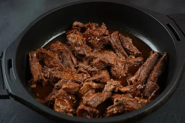 Dökme demir tavada sığır eti güveci. Dilimlenmiş et parçaları.