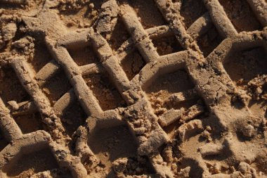 Kumda kamyon izi var. Toprak bir yolda tekerlek izi. Kamyonların tekerleklerinin izi. Araba lastiği izleri kumda, arka planda, dokuda.