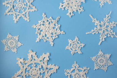 Top view of handmade white crochet snowflakes on blue background. Merry Christmas and happy new year concept.	