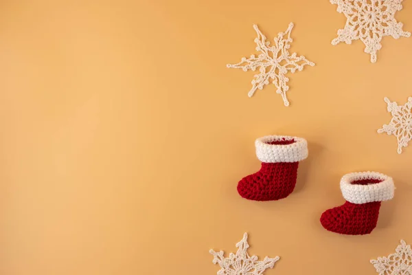 Handmade crochet stocking and white snowflake on orange pastel background. Merry Christmas and happy new year concept.
