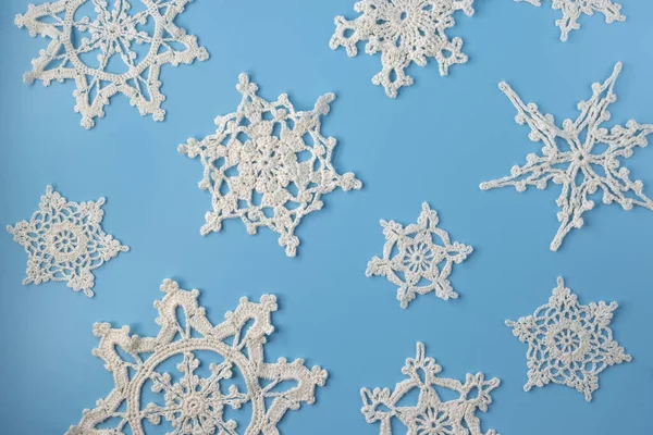 Top view of handmade white crochet snowflakes on blue background. Merry Christmas and happy new year concept.	