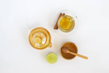 Beyaz zemin üzerinde zencefil kökü, limon, tarçın ve çaydanlık olan bir fincan çay. Sağlık içeceği kavramı.