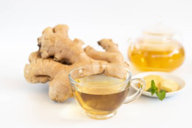 a cup of tea with ginger root, lime, cinnamon and teapot on white background. Health drink concept..	