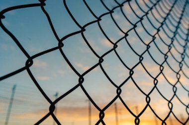 Günbatımı gökyüzünün önündeki tel örgüler.