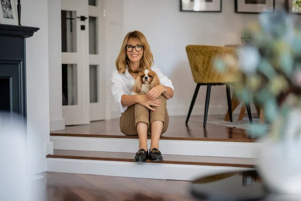 바닥에 강아지를 여성의 집에서 휴식을 취하면서 안경을 평상복을 매력적 — 스톡 사진