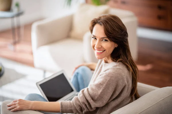 一个有魅力的中年女性坐在沙发上使用笔记本电脑的特写镜头 穿着休闲装的漂亮女人 — 图库照片