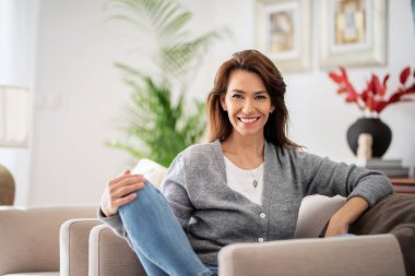 Evdeki koltukta dinlenirken günlük kıyafetler giyen güzel, uzun saçlı kadının portresi.. 