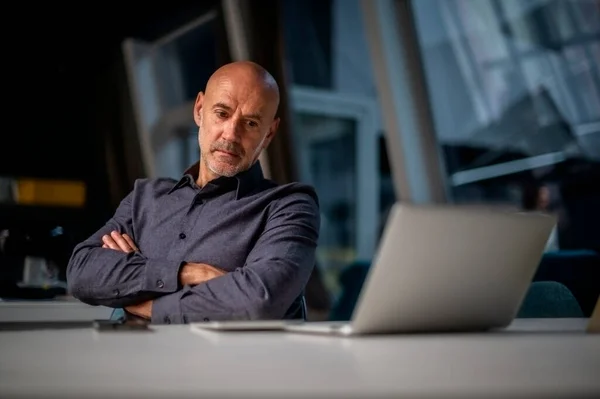 デスクに座って現代的なオフィスで働いている間 ノートパソコンを使用してビジネスマンを考えてのショット — ストック写真