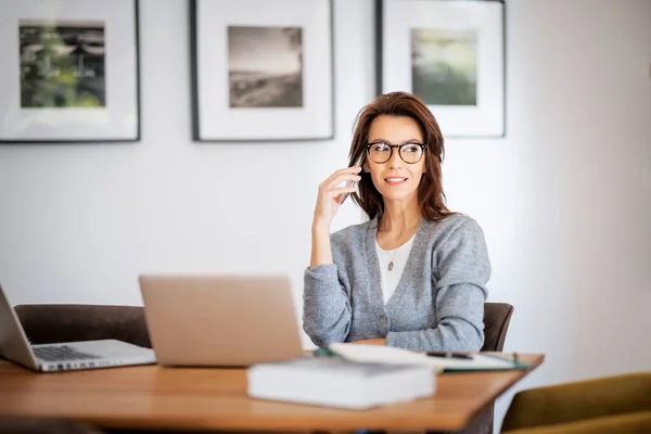집에서 일하는 안경을 평상복을 매력적 노트북을 사용하고 전화를 비지니스 여성입니다 — 스톡 사진