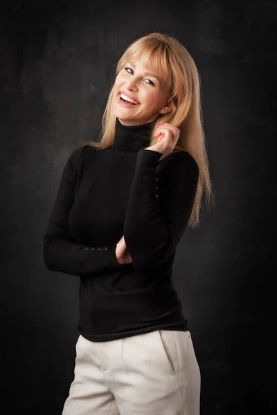 아름다운 미소짓는 여자가 어두운 배경에서 있습니다 터틀넥 스웨터를 — 스톡 사진