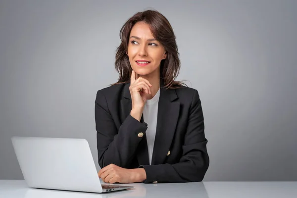 Studyjne Ujęcie Bizneswoman Patrzącej Przemyślnie Używającej Laptopa Pracy Uśmiechnięta Kobieta — Zdjęcie stockowe