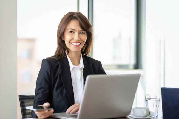 迷人的女商人穿着西装 工作时使用笔记本电脑 微笑着坐在办公室里工作的女性 — 图库照片