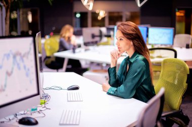 Ofiste masa başında otururken bilgisayar kullanan orta yaşlı bir iş kadını. Profesyonel kadın yeni iş projesinde çalışıyor..