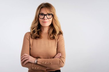 Çekici, orta yaşlı, gülümseyen ve kameraya bakan bir kadının yakın çekimi.