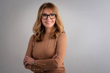 Çekici, orta yaşlı, gülümseyen ve kameraya bakan bir kadının yakın çekimi.. 