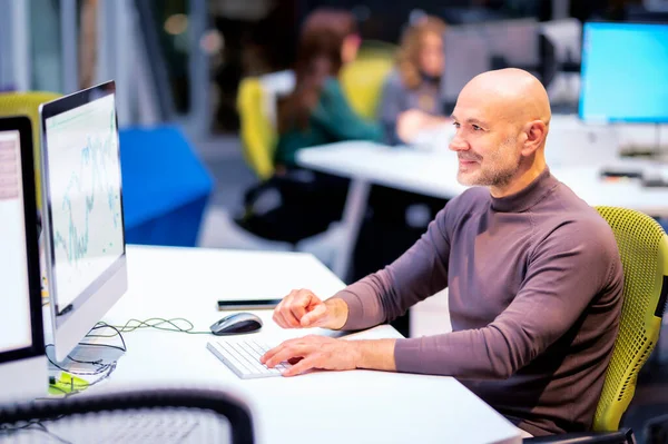 Χαμογελώντας Μεσήλικας Επιχειρηματίας Που Κάθεται Στο Γραφείο Και Χρησιμοποιεί Υπολογιστές — Φωτογραφία Αρχείου