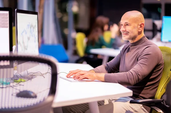 中年商人坐在写字台前 用电脑工作 职业男性穿着休闲装 面带微笑 — 图库照片