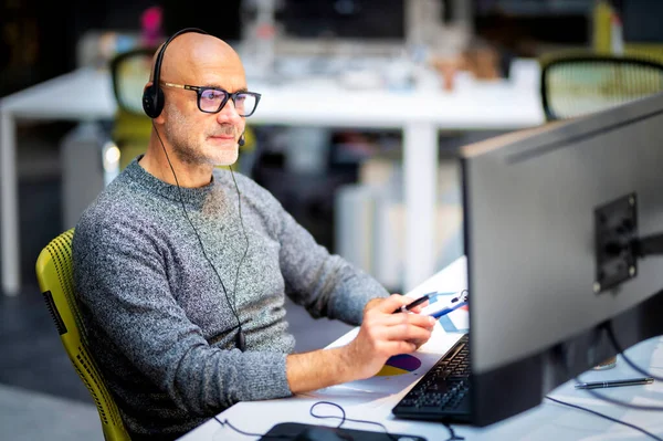 Reifer Geschäftsmann Mit Kopfhörern Sitzt Tisch Und Arbeitet Computer — Stockfoto
