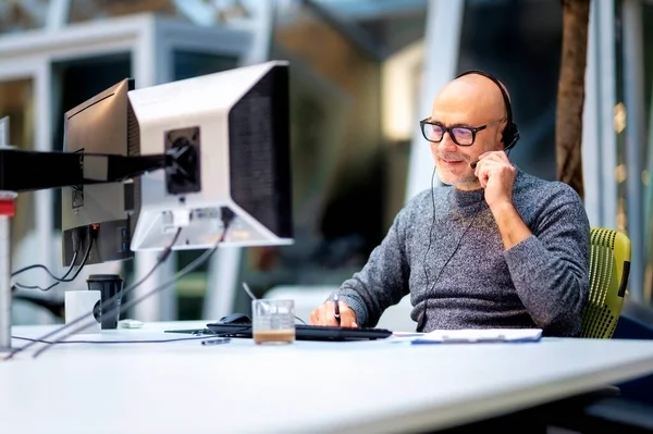 Dojrzały Biznesmen Słuchawkami Siedzący Przy Stole Pracujący Komputerach Mężczyzna Obsługa — Zdjęcie stockowe