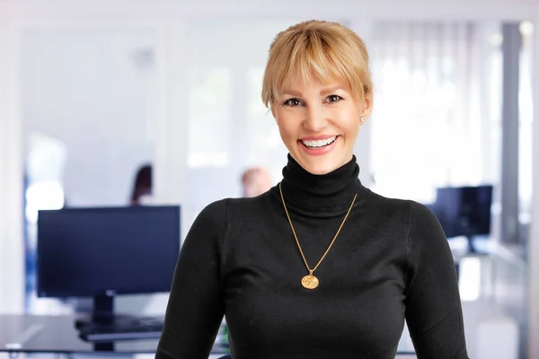 中年のプロの女性の笑顔とカメラを見てのクローズアップ オフィスにいる間にセーターを着てブロンドの髪のビジネスマンの女性 スペースのコピー — ストック写真