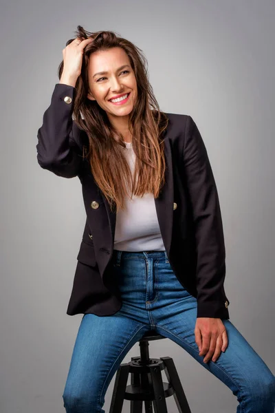 Studio Portrait Attractive Woman Wearing Blazer Blue Jeans While Sitting — Stock Photo, Image