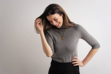 Çekici esmer, neşeli saçlı, gülümseyen ve izole bir arka planda duran bir kadın. Orta yaşlı kadın balıkçı yaka kazak giyiyor.. 