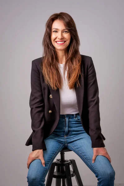 Χαμογελαστή Μελαχρινή Επιχειρηματίας Κάθεται Πάνω Γκρι Φόντο Γυναίκα Αυτοπεποίθηση Φοράει — Φωτογραφία Αρχείου