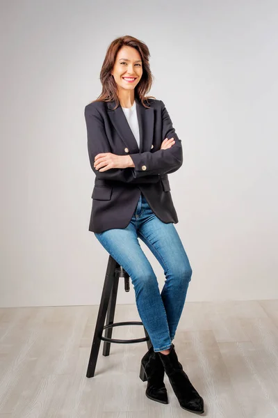 Estúdio Retrato Mulher Atraente Vestindo Blazer Jeans Azuis Enquanto Sentado — Fotografia de Stock