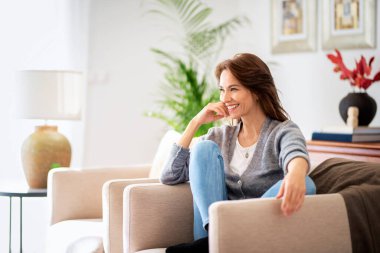 Evdeki koltukta dinlenirken günlük kıyafetler giyen güzel, uzun saçlı kadının portresi.. 