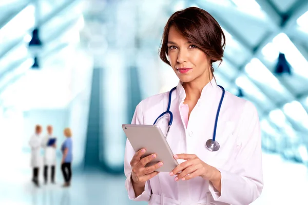 一名女医生站在医院走廊时拿着数码平板电脑的画像 — 图库照片