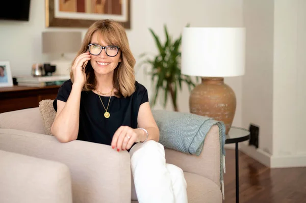 一个有魅力的中年女人坐在家里打电话的画像 金发女人戴着眼镜和黑色衬衫 总部办公室 — 图库照片