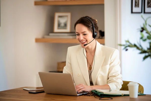 客户服务助理坐在电脑前 头戴耳机 在呼叫中心工作 有魅力的女商人穿着白色西装 图库图片
