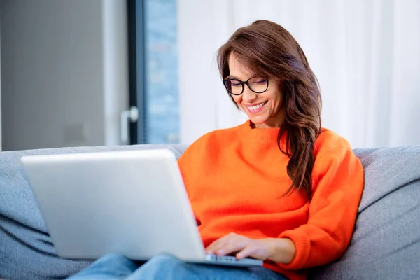 Tiro Mulher Feliz Usando Seu Laptop Enquanto Sentada Sofá Casa — Fotografia de Stock