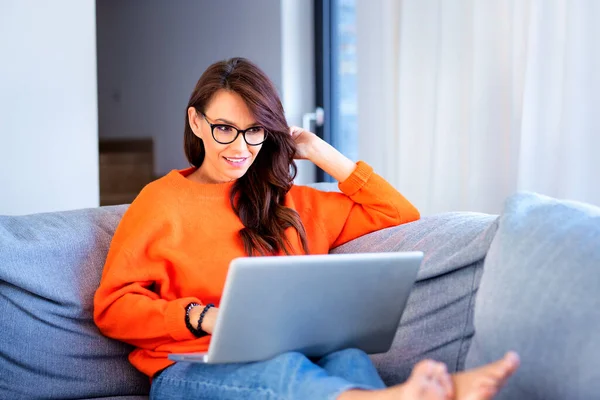 Mutlu Bir Kadının Evdeki Kanepede Otururken Bilgisayarını Kullanırken Internetten Video — Stok fotoğraf