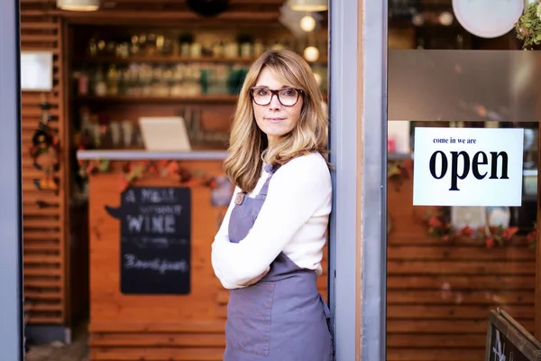 一位自信的女店主站在咖啡店门口的画像 布鲁内特留着漂亮的头发 看着相机 面带微笑 — 图库照片